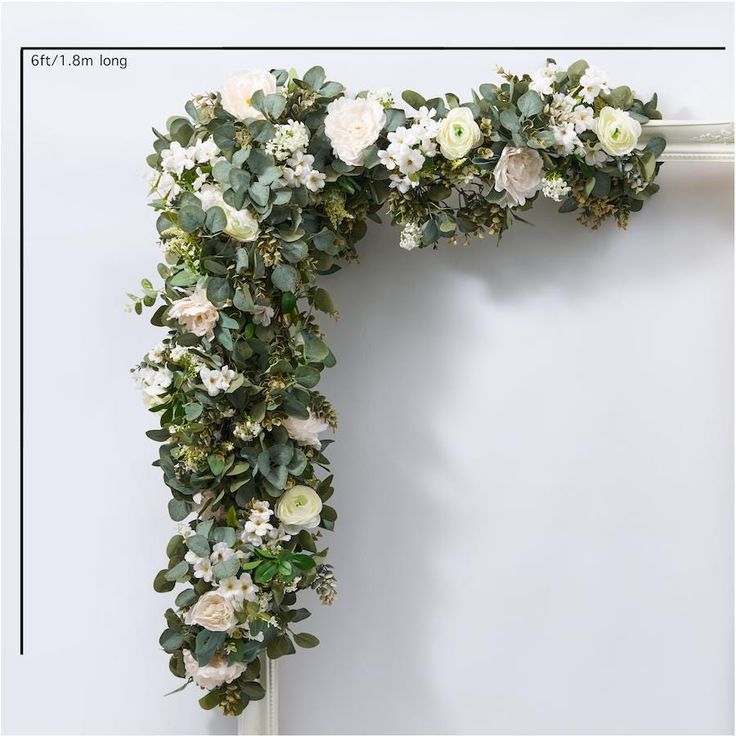 a white flower and greenery arch hanging on a wall