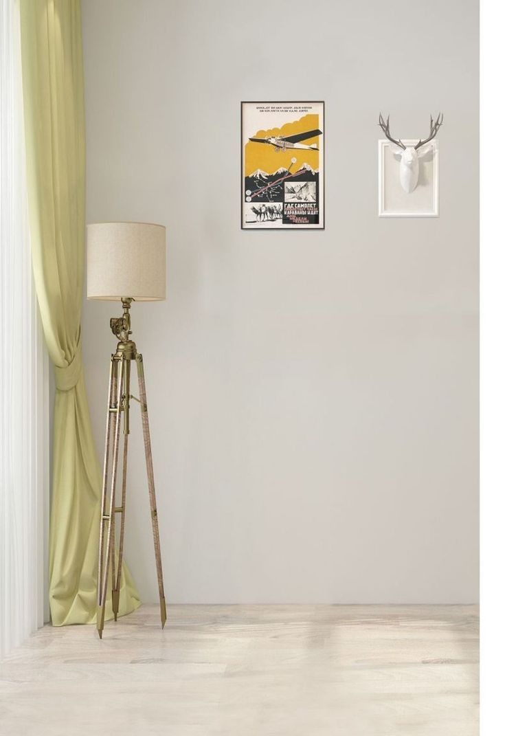 a room with a lamp and pictures on the wall next to a tripod stand