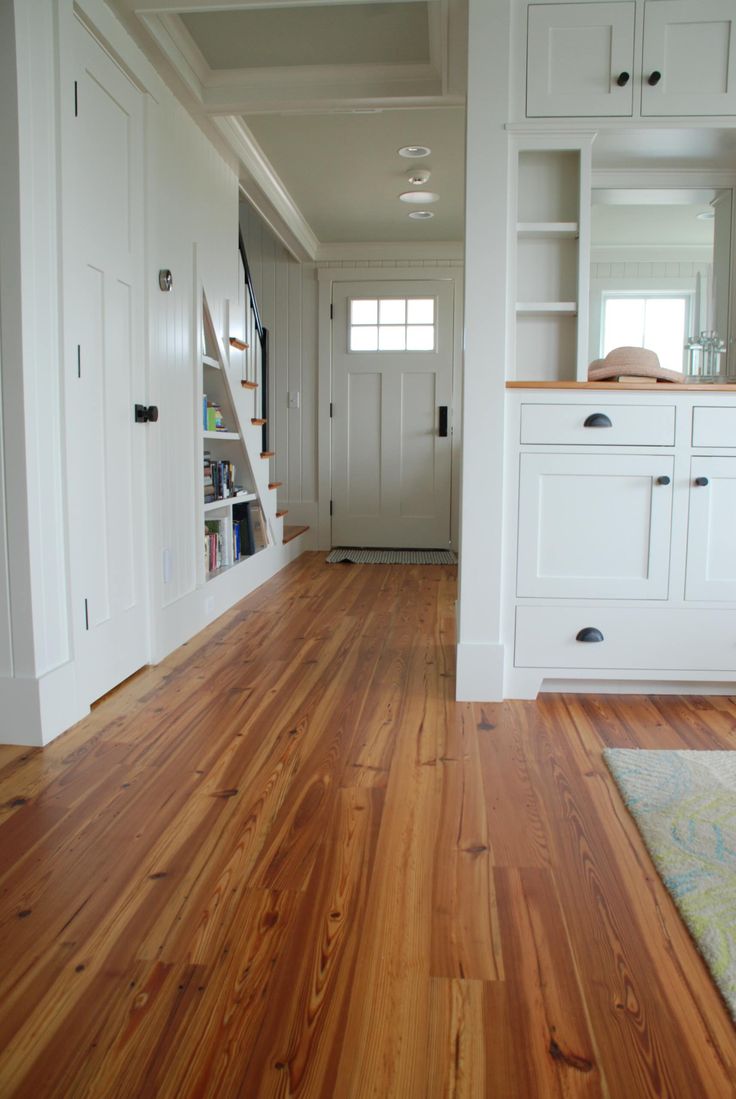 an empty kitchen with white cabinets and wood flooring, along with a rug on the floor