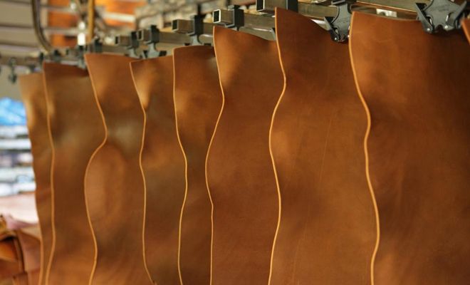 several brown leather bags are hanging on a rack