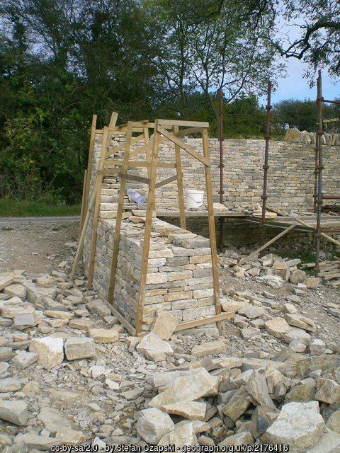 a pile of rocks with a wooden structure in the middle surrounded by trees and bushes