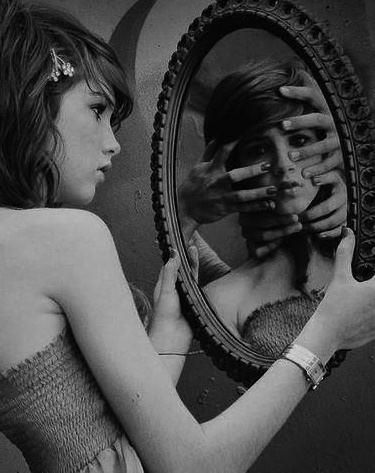 a woman in a pink dress holding a mirror with her face painted on the wall