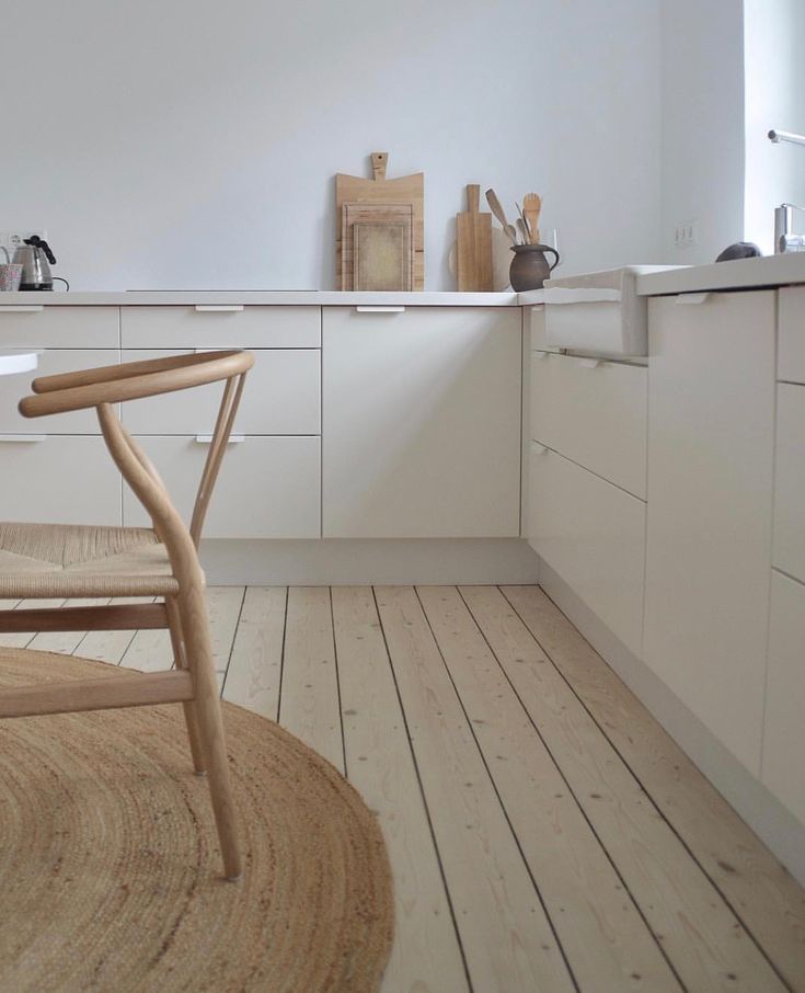 a kitchen with white cabinets and wooden floors