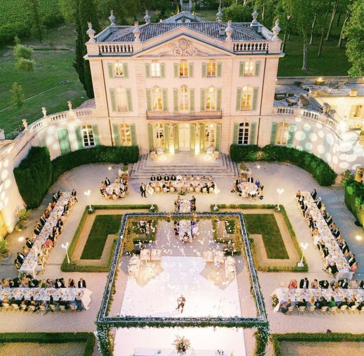 an aerial view of a large building with lots of people sitting around the courtyard and lawn