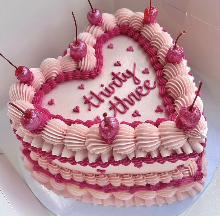 a heart shaped birthday cake with pink frosting