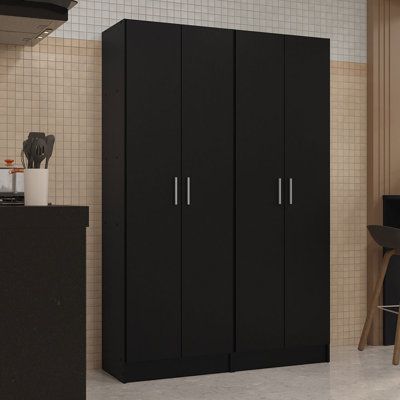 a black cabinet in a kitchen next to a table and chair with a laptop on it