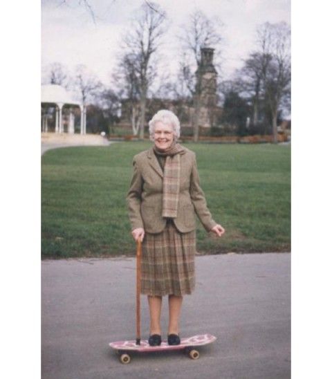 an older woman is standing on a skateboard