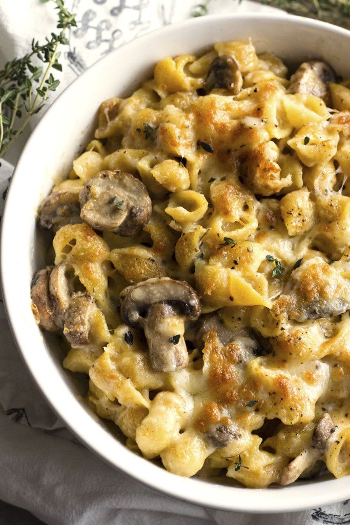 a bowl filled with pasta and mushrooms on top of a white cloth next to a fork