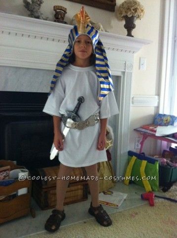 a young boy dressed up as an egyptian god in front of a fire place and fireplace