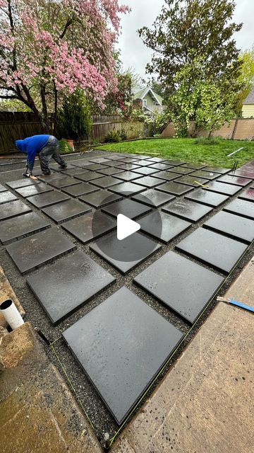 a man is working on an outdoor patio with black tiles and waterproof membranes