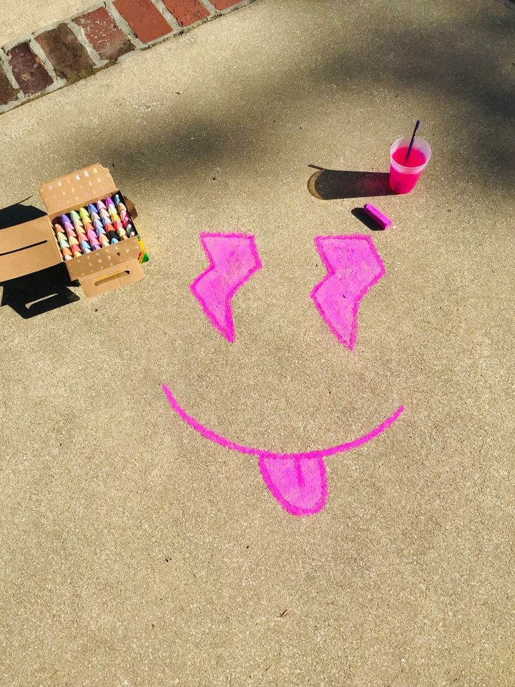 a child's sidewalk drawing with crayons on it and a chair next to it