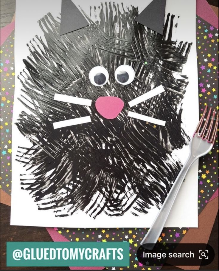 this is an image of a cat made out of black crinkle paper with a fork