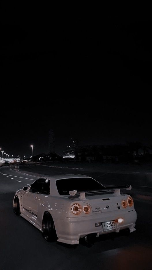 the white car is parked on the side of the road at night time in the city