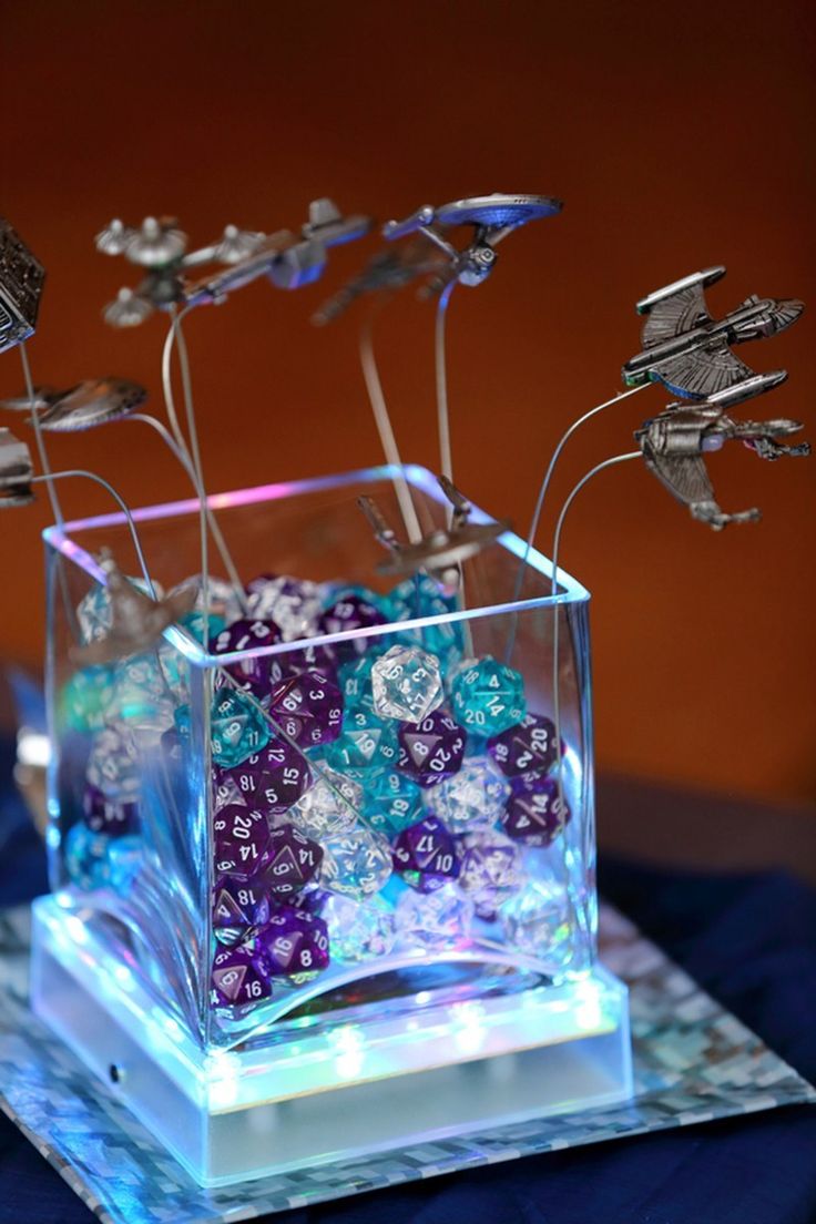 a glass vase filled with purple and blue flowers on top of a table next to a plate