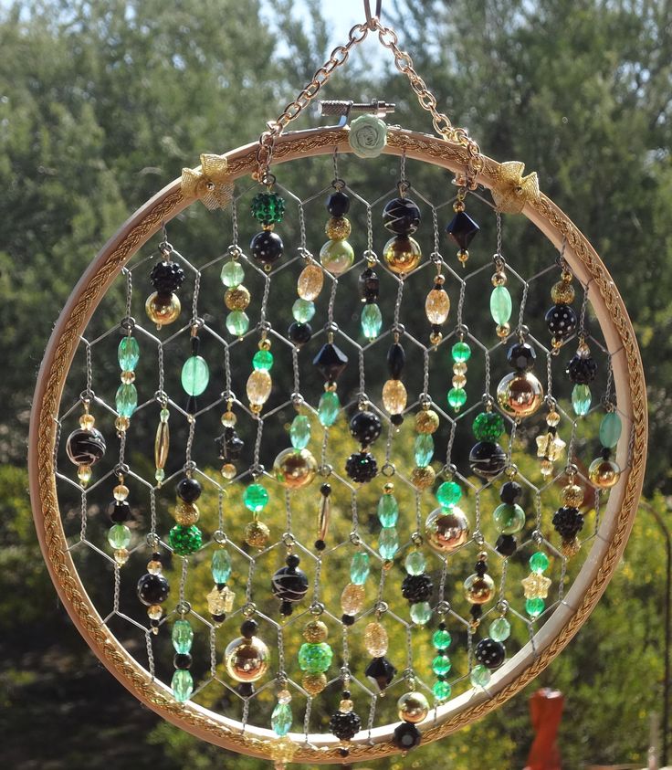 a wind catcher with many different colored beads hanging from it's side and trees in the background