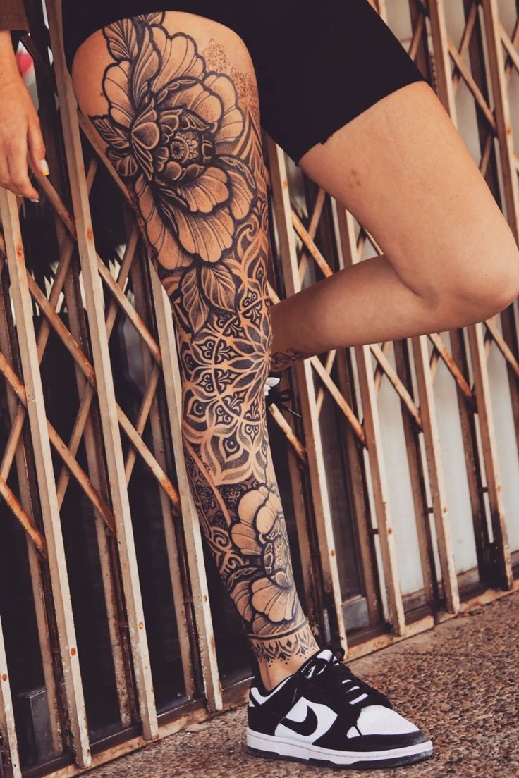 a woman's legs with tattoos on them and flowers in the middle of her leg