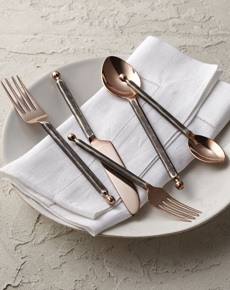 three forks and two spoons on a white plate