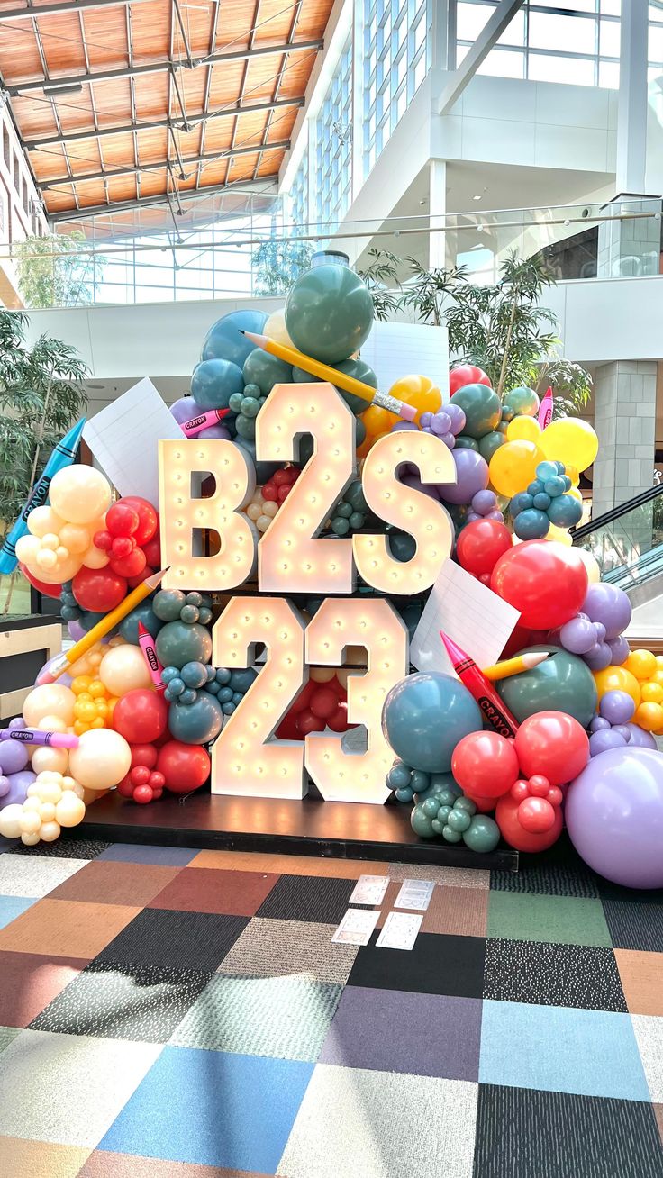 the letters b2s are surrounded by balloons and streamers in an airport lobby