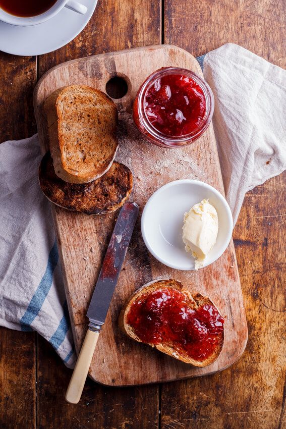 a wooden cutting board topped with bread and jam