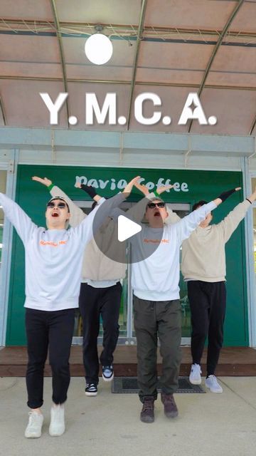 four people standing in front of a building with their arms up