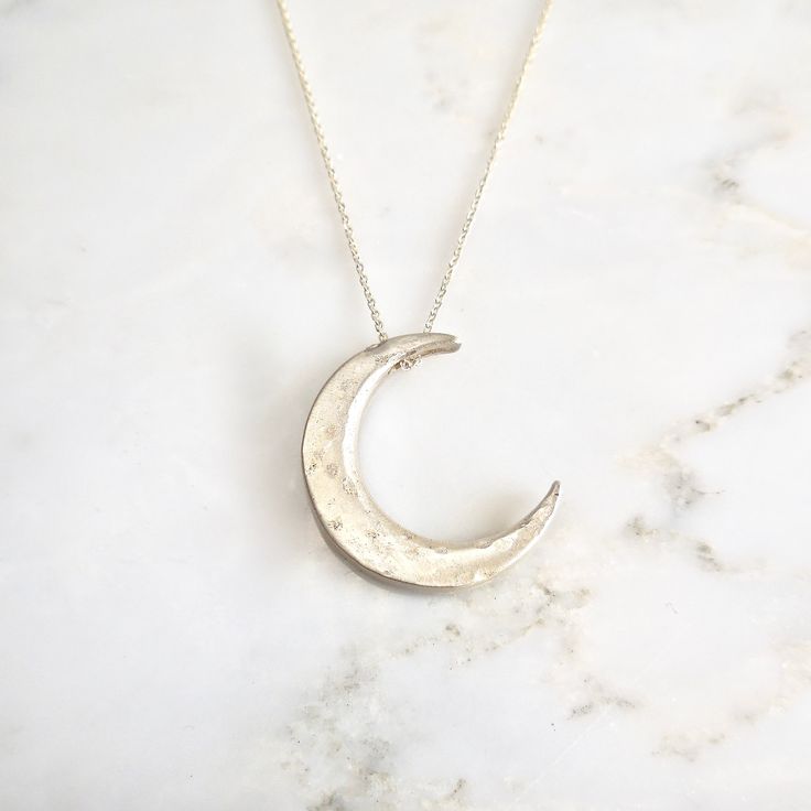 "This unique crescent moon phase pendant is available in silver or 14 k gold. So beautiful polished but equally stunning hand-finished matte, hammered or have it encrusted with diamonds. A focal piece that can be stacked with smaller pendants. It's a slide providing space for a pendant to fit into the opening. We've paired it with our bezel set moonstone. crescent moon 24 millimeters long x 19 mm wide or/ almost 1\" long x 3/4\" wide 14k solid gold or sterling silver pave Diamond encrusted Cresc Silver Crescent Moon Charm Jewelry, Minimalist Crescent Hammered Jewelry, Hand Forged Sterling Silver Celestial Necklace, Minimalist Hammered Crescent Jewelry, Engraved Sterling Silver Crescent Jewelry, Elegant Crescent Hammered Jewelry, Elegant Hammered Crescent Jewelry, Elegant Crescent Shaped Hammered Jewelry, Celestial Crescent Sterling Silver Jewelry