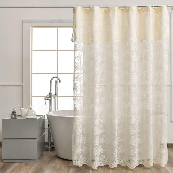 a bath tub sitting next to a shower curtain in a bathroom with wooden floors and white walls