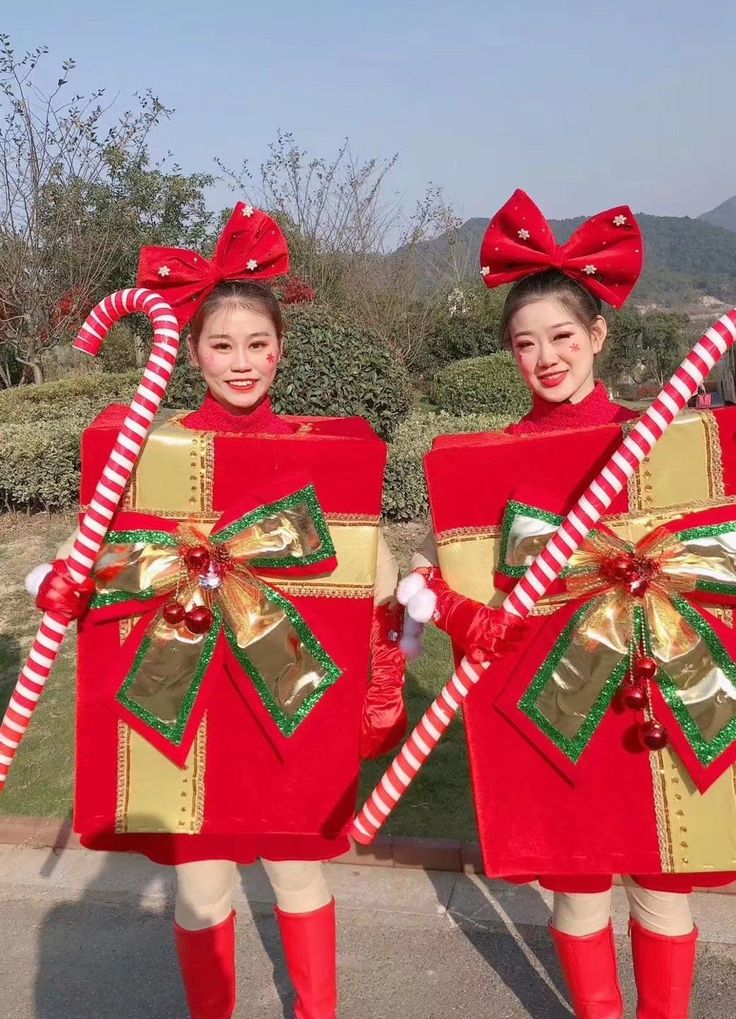 two girls dressed in red and gold holding candy canes