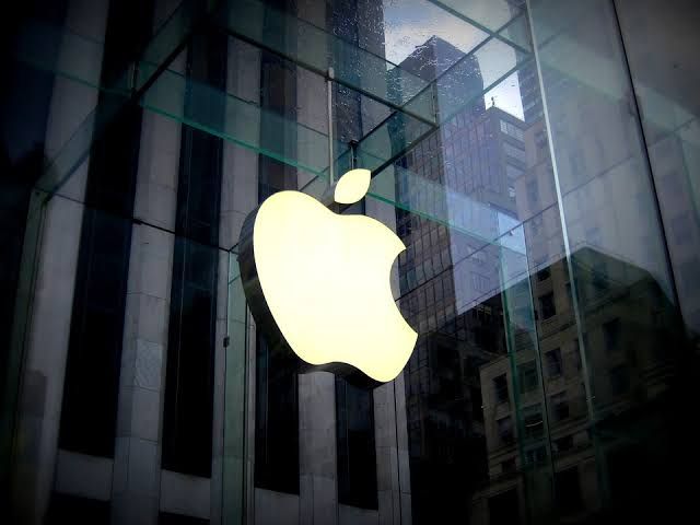 an apple logo is seen in front of a glass building