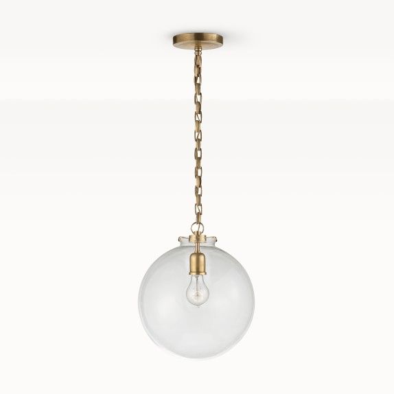 a glass globe light hanging from a brass chain