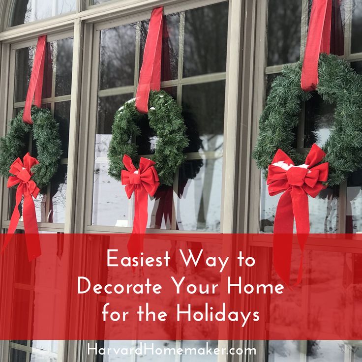 wreaths with red bows hanging from the windows