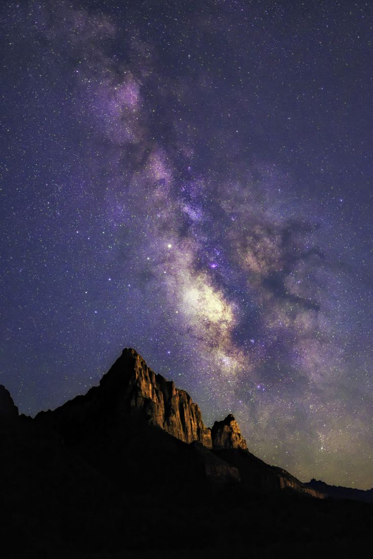 the night sky is filled with stars and bright purple lights, as well as some mountains