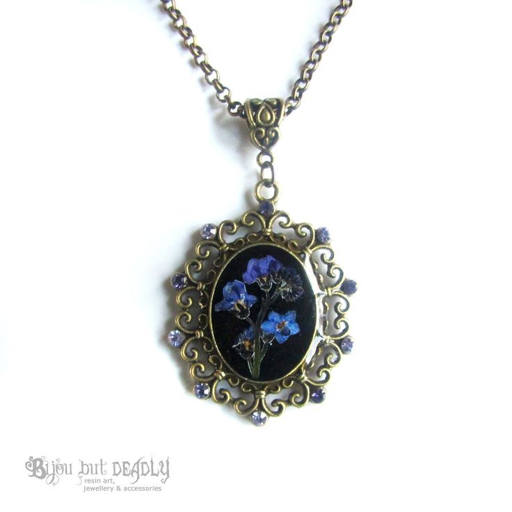 "An ornate Victoriana cameo necklace from the Bijou Botanicals range. This necklace features an arrangement of real, pressed forget-me-nots set against a black background. A Swarovski crystal drop bead hangs from the pendant. Bronze plated chain with extender and custom BBD hang tag! SIZING Chain length: 41cm (16\") Extender length: 5cm Approx size of pendant: 3.7 x 3cm PACKAGING Presented in an organza pouch and includes a polishing cloth. PLEASE NOTE: This item is made to order and takes an ad Antique Flower Pendant Necklace Gift, Antique Flower Pendant Necklace For Gift, Antique Flower Pendant Necklace As Gift, Vintage Charm Flower Pendant Jewelry Gift, Vintage Flower Pendant Jewelry As Gift, Vintage Charm Jewelry With Flower Pendant For Gift, Cabochon Brass Jewelry For Gifts, Gift Brass Cabochon Jewelry, Gift Brass Jewelry With Cabochon