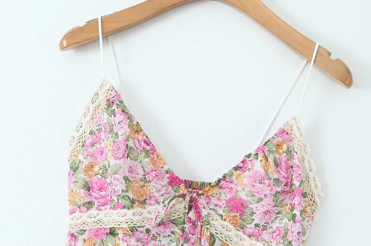 a pink flowered top hanging on a wooden hanger next to a white wall