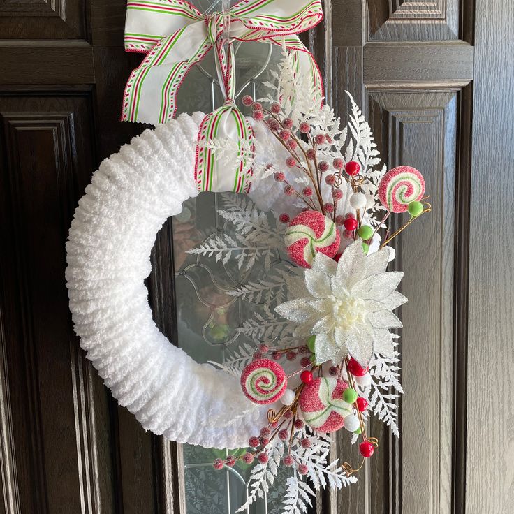 a wreath with candy canes and flowers hanging on a door