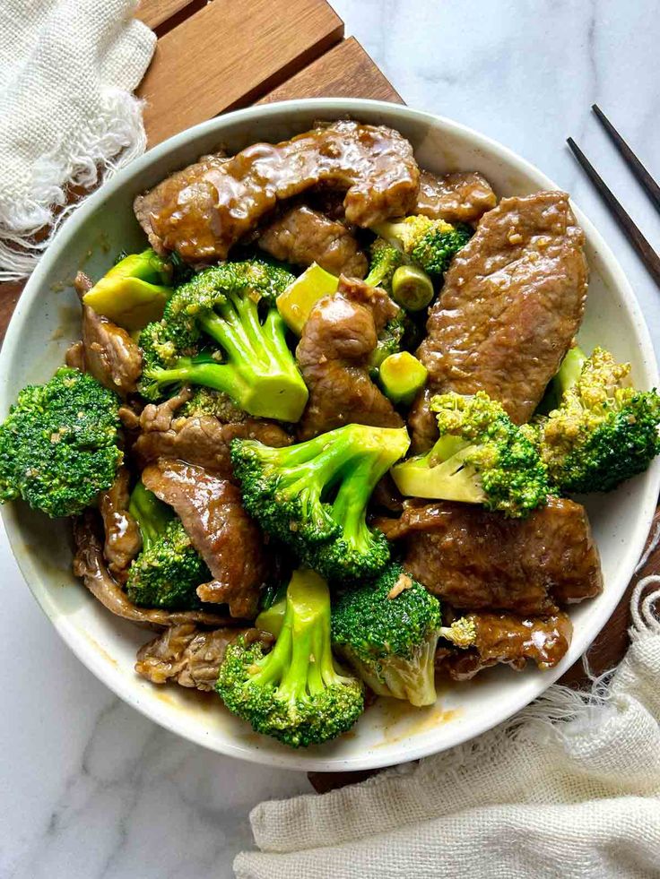 beef and broccoli stir fry in a bowl with chopsticks on the side