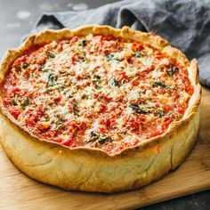 a pizza sitting on top of a wooden cutting board next to a gray napkin and knife