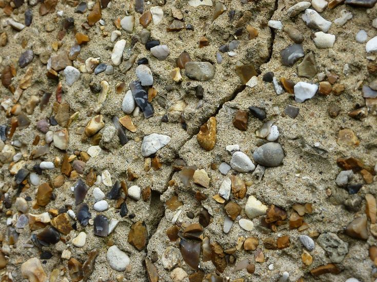 rocks and gravel on the side of a rock wall, with small stones embedded in them