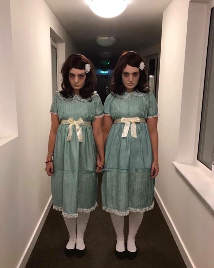 two young women dressed in green dresses standing next to each other on a hallway way