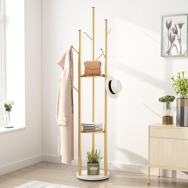 a white room with a coat rack, hat stand and potted plant in it