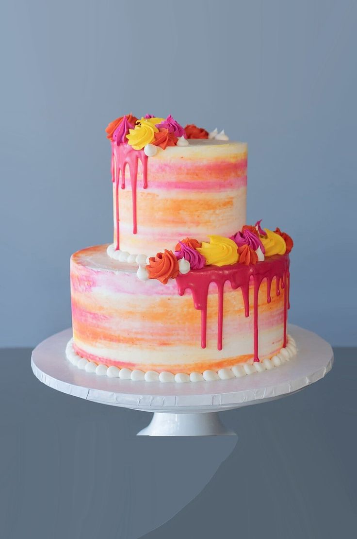 a multi layer cake with dripping icing and flowers