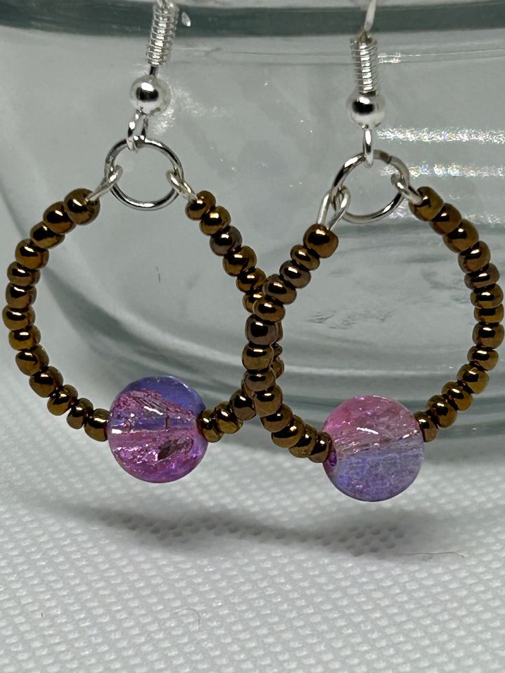 These lovely hoop earrings give off galaxy vibes with their copper colored seed beads and pink/purple glass focal beads, which are situated on a wire earring hoop. They are approximately 1.5 inches in length and are for pierced ears. They are secured in place by rubber earring backings. Wear them with everyday outfits or as an accent piece. They are sure to add something extra to your earring collection! Galaxy Ring, Purple Glass, Wire Earrings, Earrings Collection, Focal Bead, Jewelry Earrings Hoops, Accent Pieces, Pink Purple, Ear Piercings