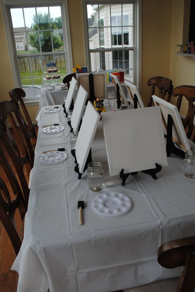 a long table is set up for an art party with easels and canvases