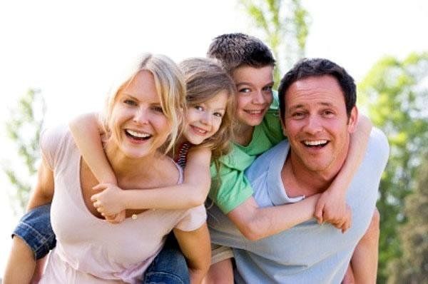 a man, woman and two children are smiling for the camera with their arms around each other