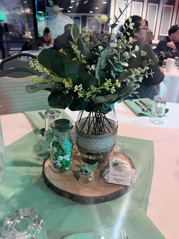 there is a vase with flowers in it on top of a wooden stand at the table