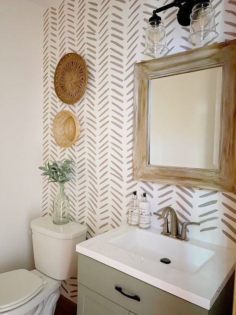 a white toilet sitting next to a bathroom sink under a wooden mirror mounted on a wall