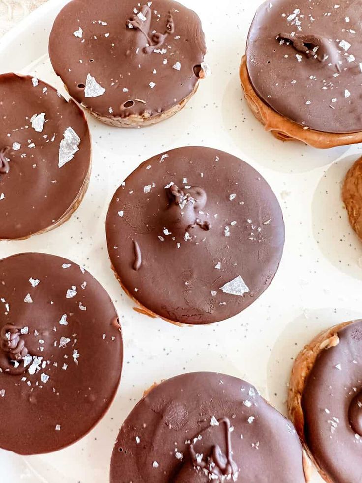 chocolate covered doughnuts on a plate with sprinkles and powdered sugar