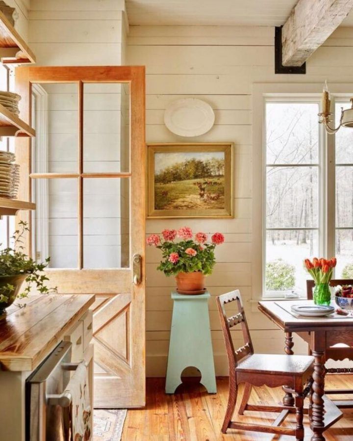 a table and chairs in a room with wooden floors, white walls and wood flooring