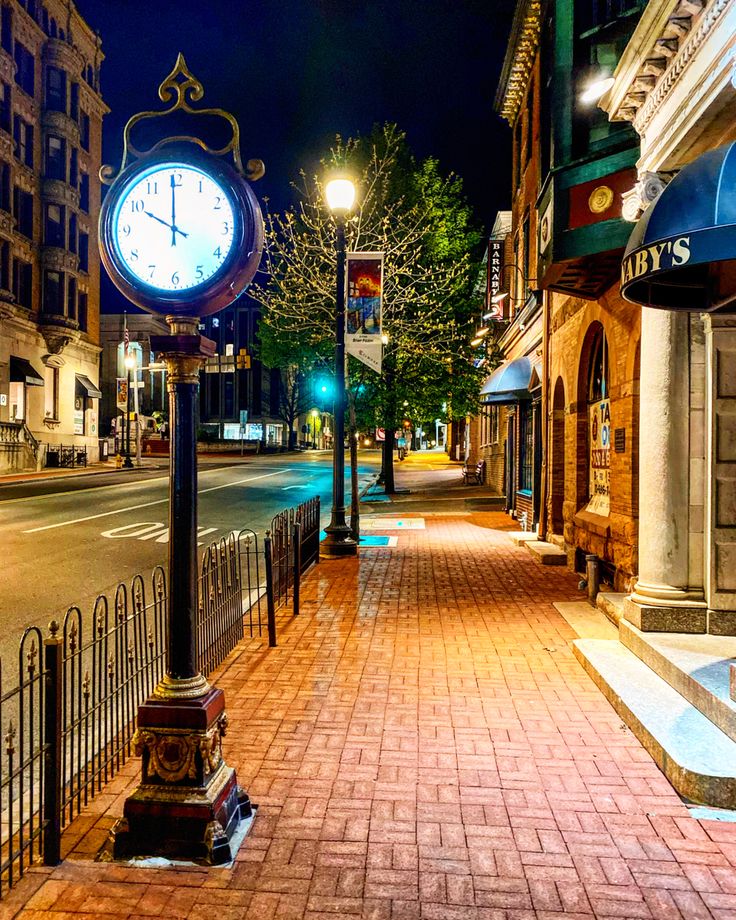 a clock on the side of a street at night