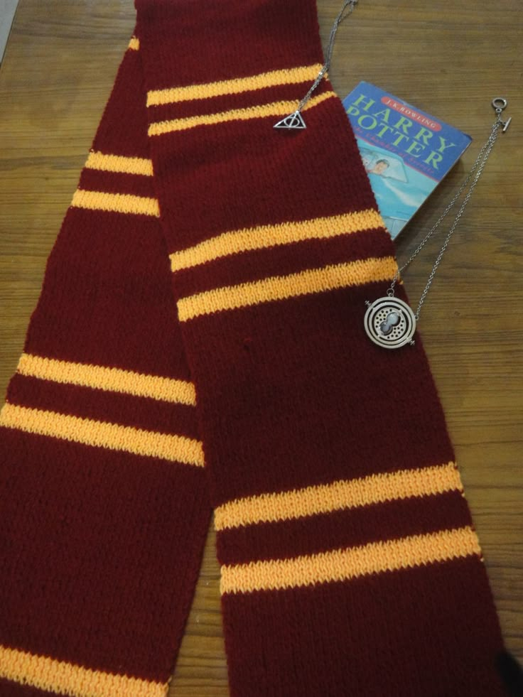 a pair of harry potter scarfs laying on top of a wooden floor next to a book