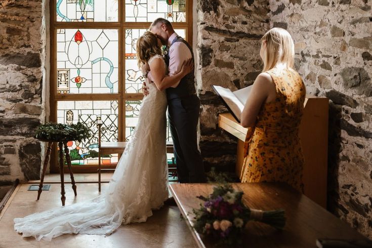 a bride and groom standing in front of a stained glass window at their wedding ceremony